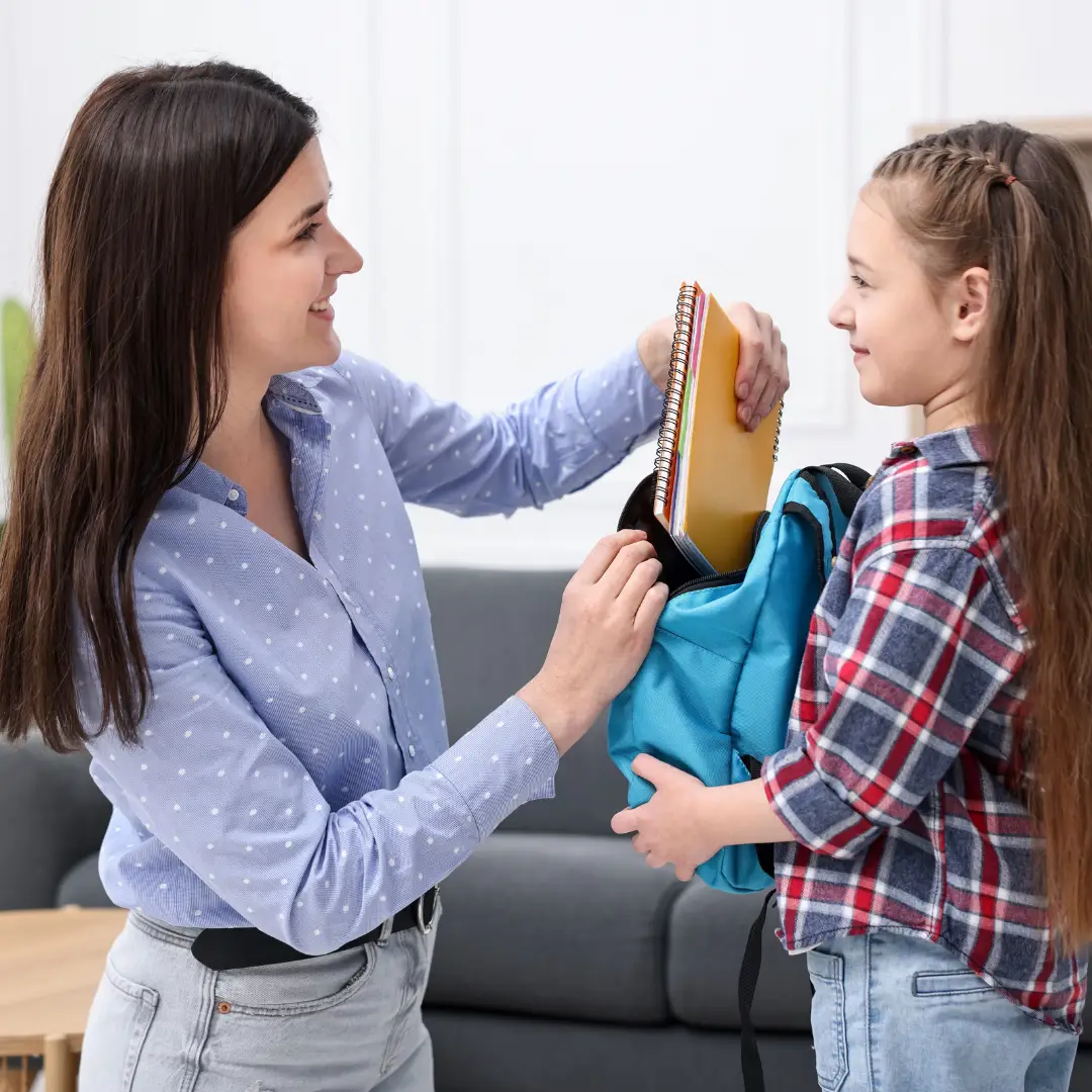 Parent helping their child pack a school bag before starting secondary school.