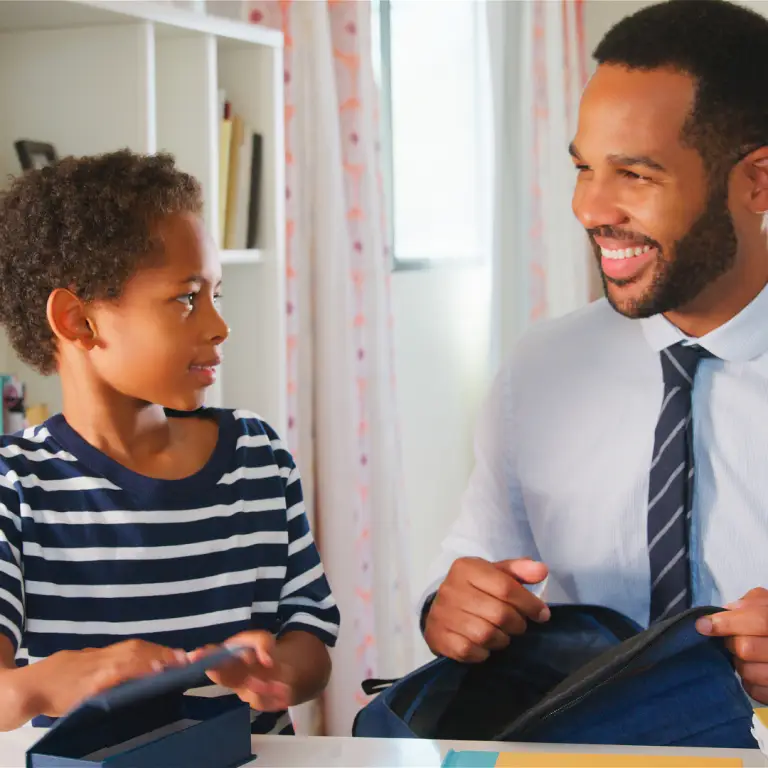 Parent helping their child organise a school bag before starting secondary school.