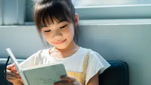 Child reading a book to improve 11+ reading comprehension skills.