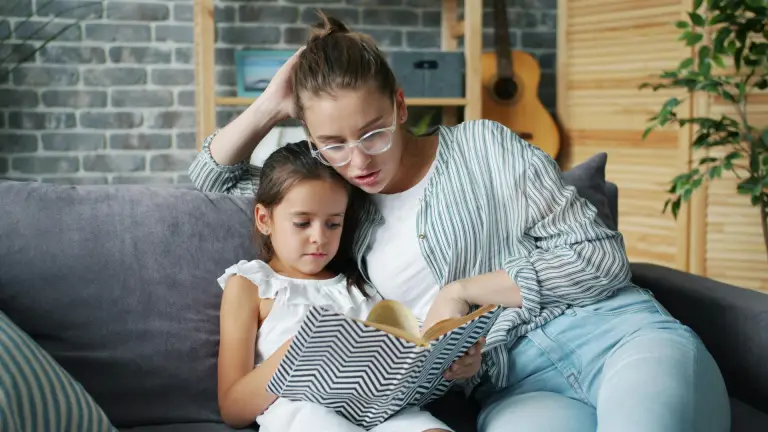 Parent reading a book with their child to encourage learning during the summer holidays.