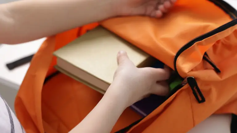 Child packing a school bag before returning to school in September.