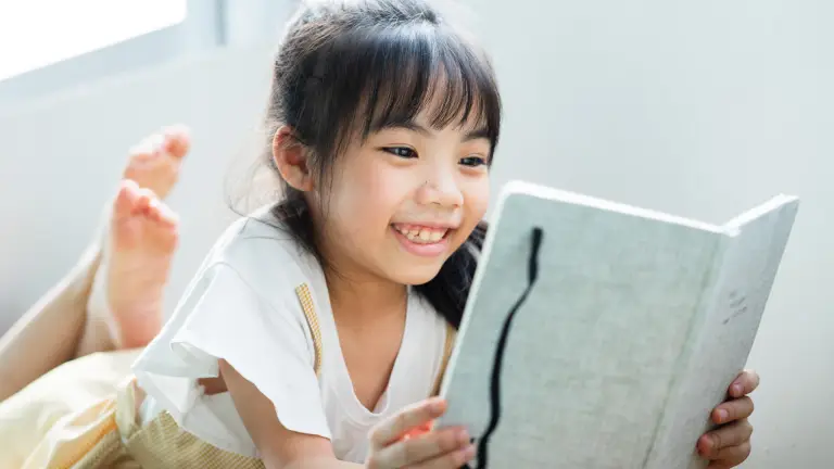 Child reading a book at home to stay confident before returning to school.