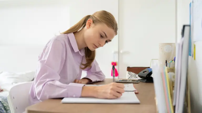 Student studying for a GCSE English resit using notes and a laptop.