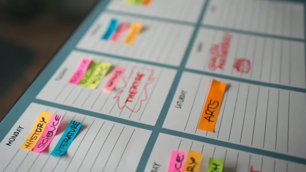 Revision timetable with notebooks, coloured pens and study materials arranged on a desk.